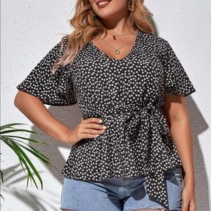 A blouse with Small daisies with a knot tie on the front.